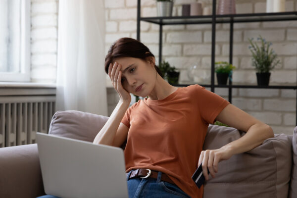 woman upset looking at laptop and holding credit card