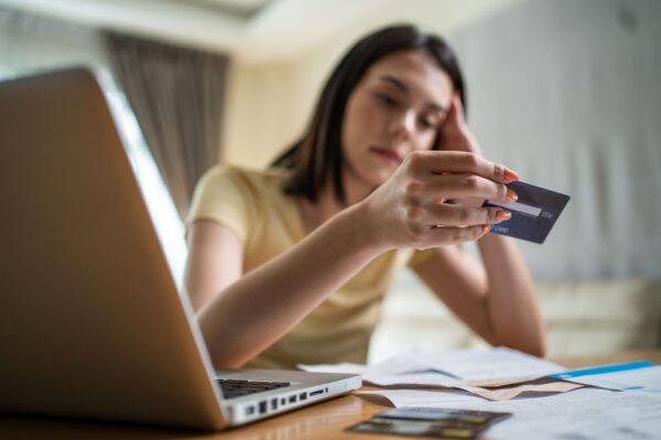 woman looking at credit card bills in front of laptop - identity theft victims