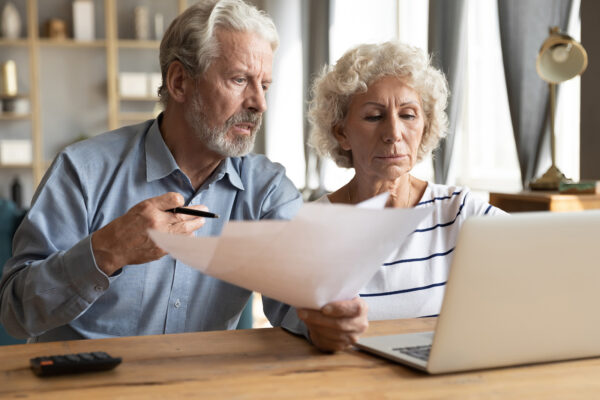 older couple looking papers and a laptop