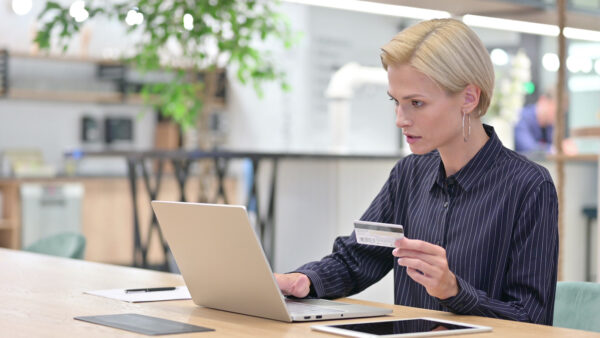 woman holding credit card looking at laptop